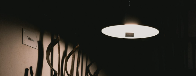 Atmosférický záber na svietiacu lampu v tmavom interiéri dielne.